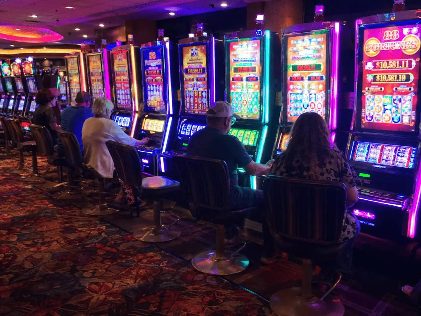 A classic poker machine cabinet beside a laptop showing an online version for comparison.